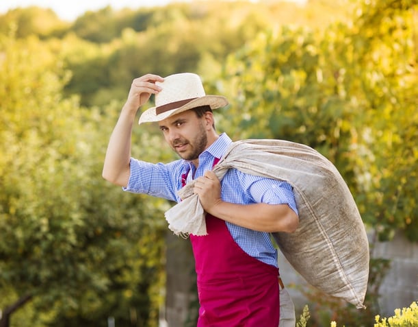 A farmer tips his hat as he carrys a PP woven bag of coffee beans